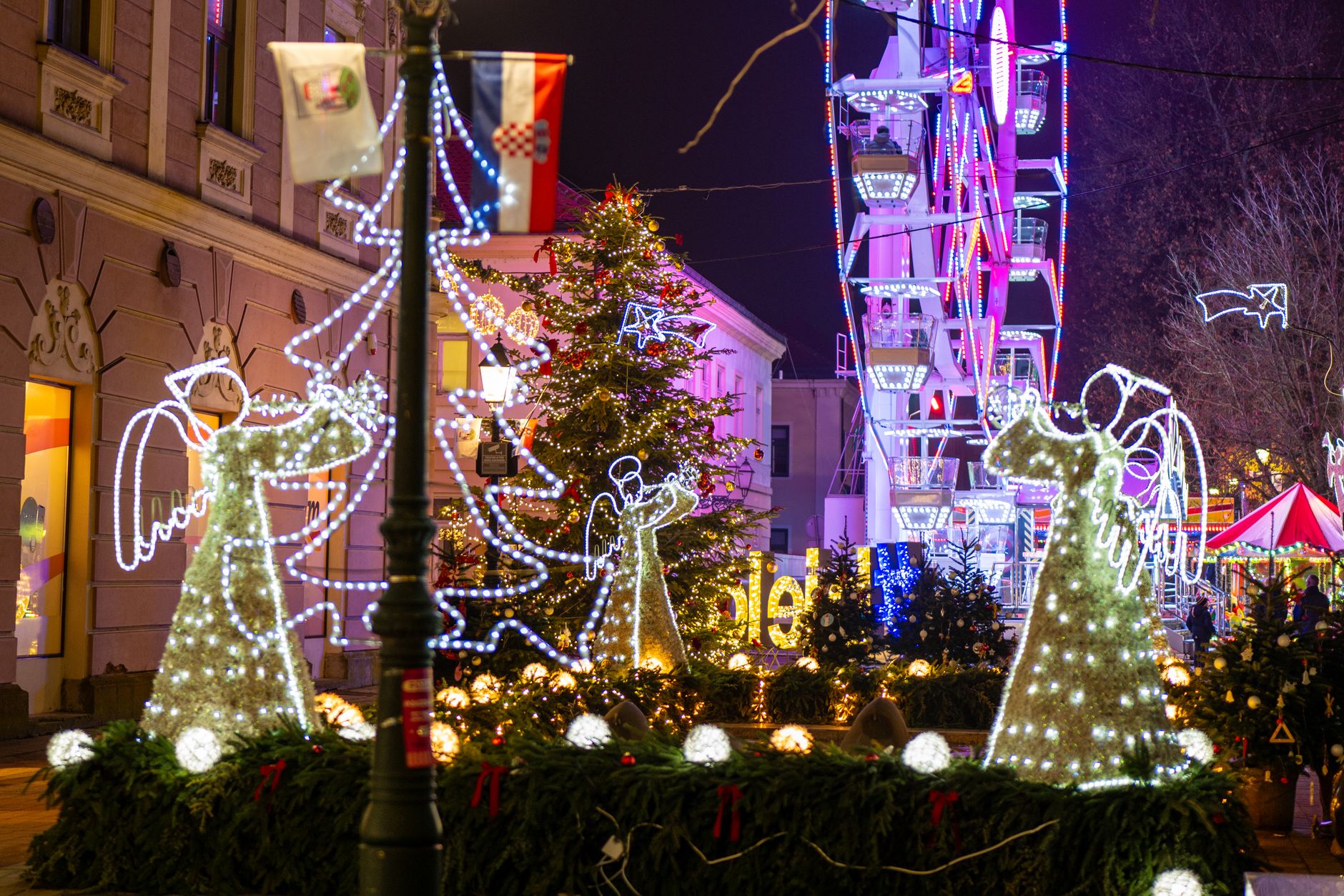 Enchanting Christmas lights and decorations in Bjelovar, Croatia, featuring holiday angels and a Ferris wheel.